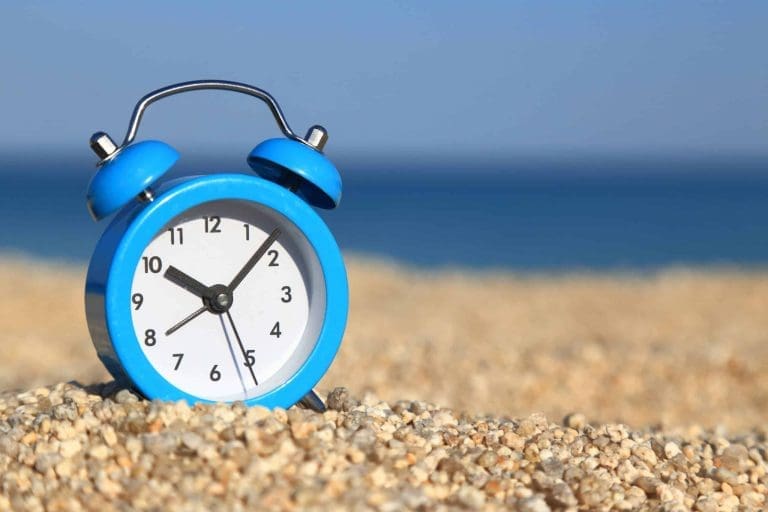 Réveille-matin bleu posé sur le sable d'une plage