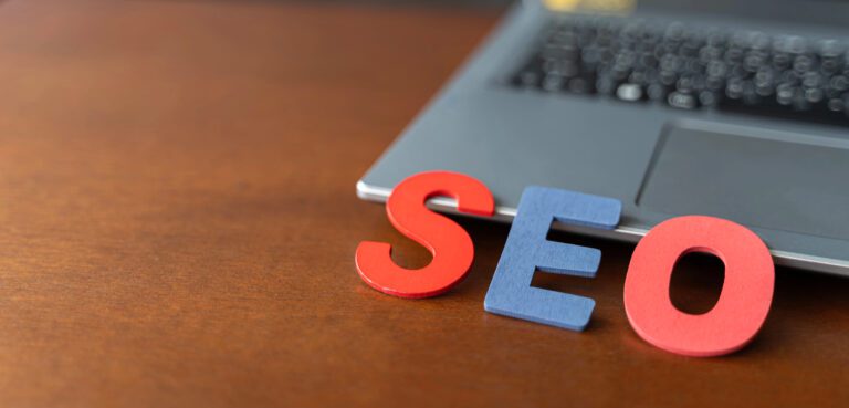 Lettres SEO en bois appuyées sur un ordinateur portable