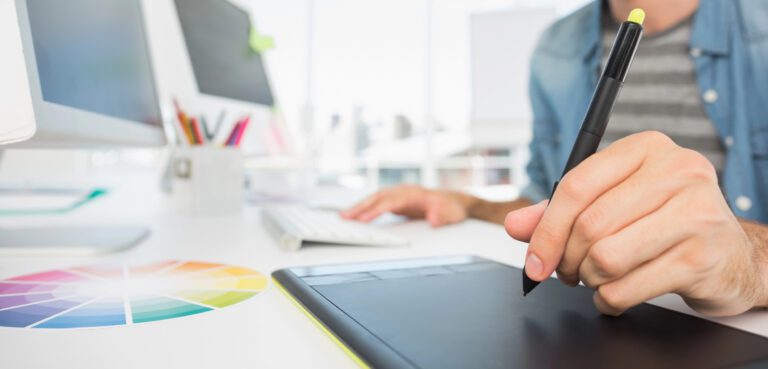 Graphiste utilisant une tablette graphique à côté d'un nuancier de couleurs